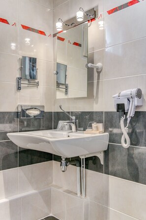 A modern bathroom with a large sink, a mirror, and a hairdryer mounted on the wall. - Le Berry (Saint-Nazaire)