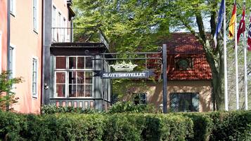 A building with a sign reading "Slottsshotellet" and flags in the background.