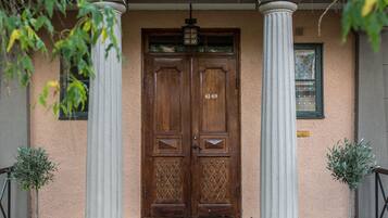 A building entrance with a wooden double door, two white columns, and a small window above the door.