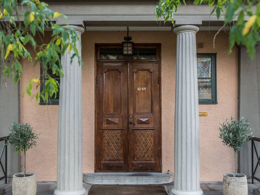 A building entrance with a wooden double door, two white columns, and a small window above the door.