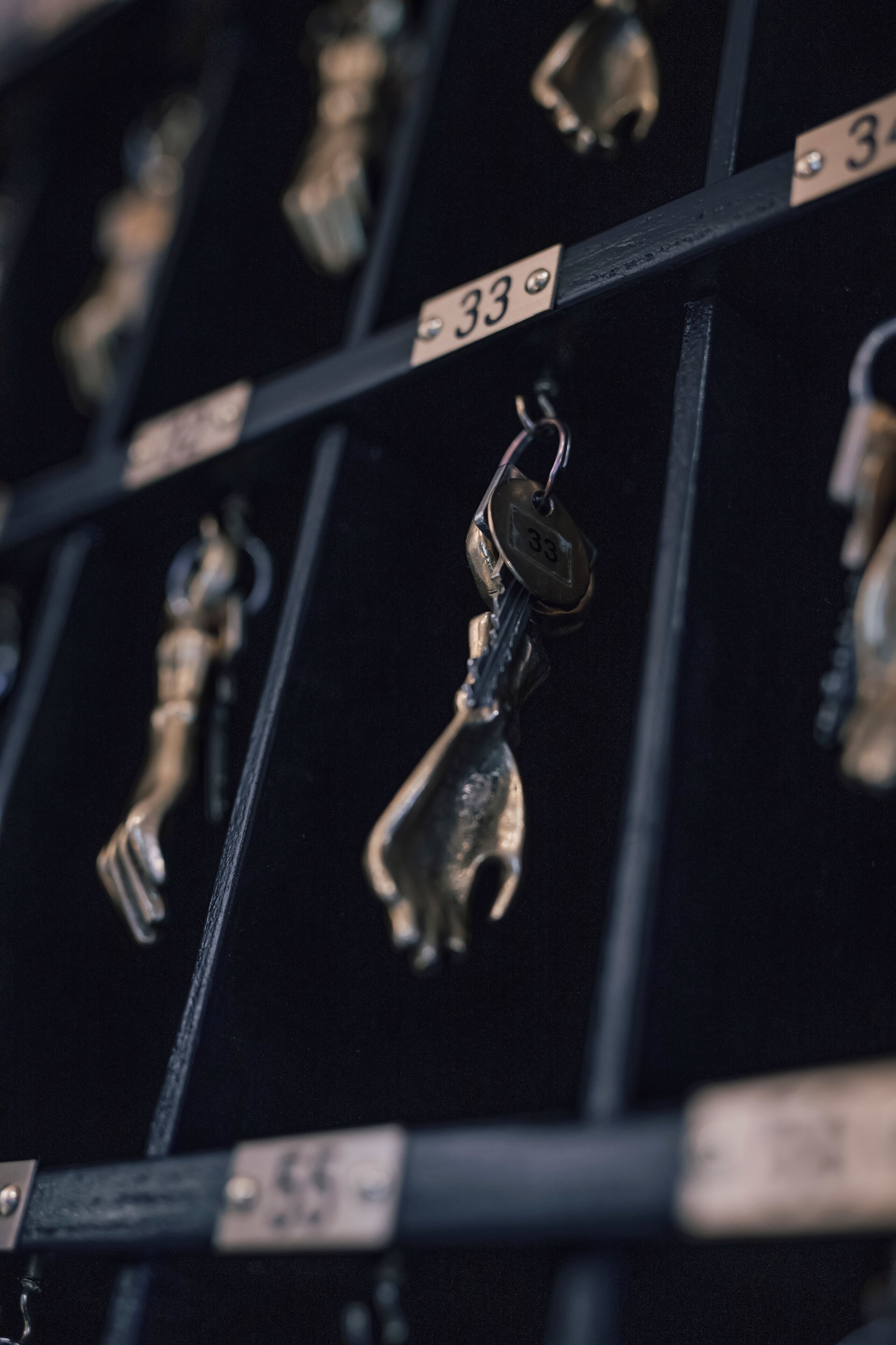 A close-up of a metal keychain with a tag labeled "33" hanging from a black metal rack.