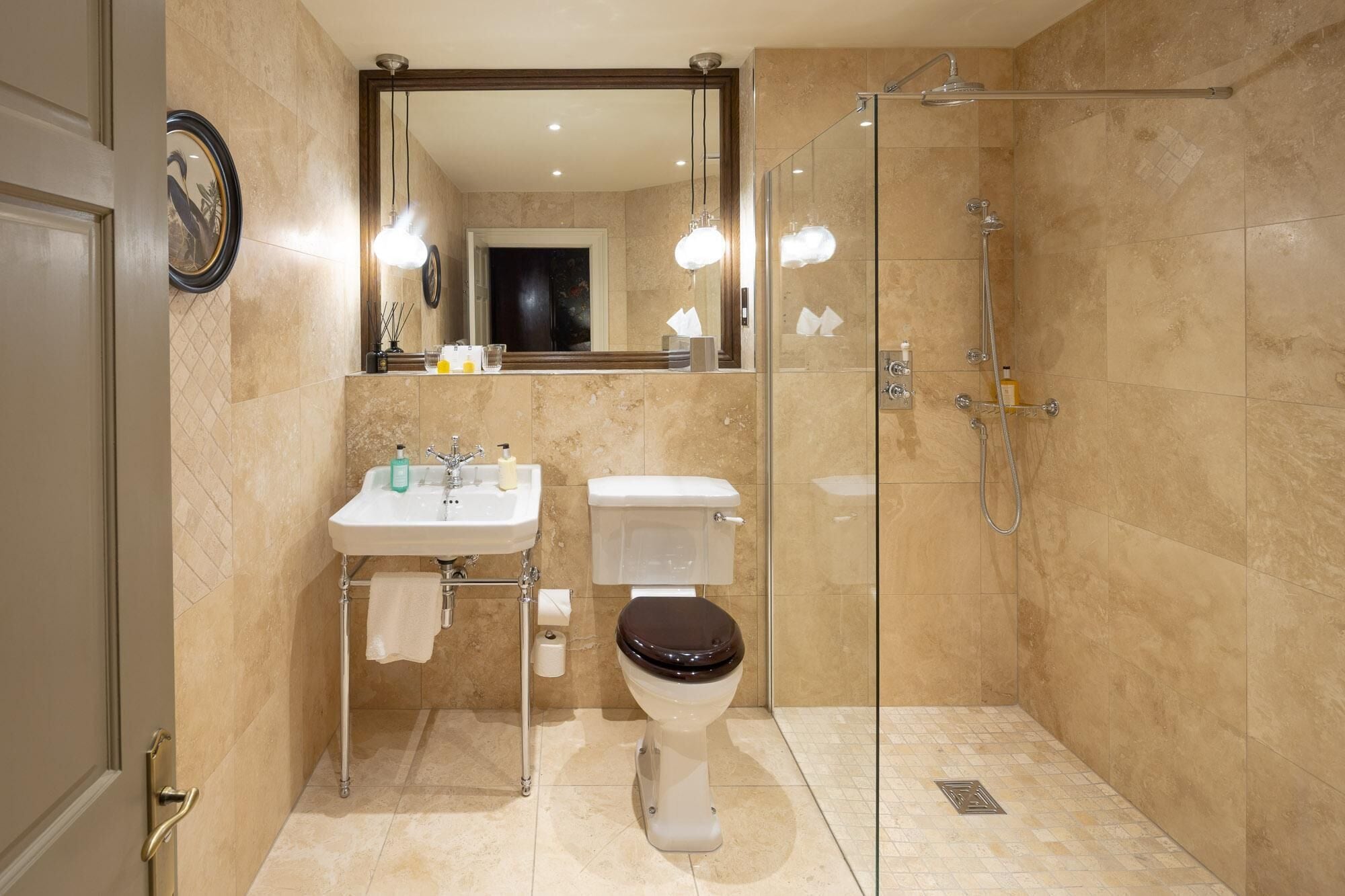 Ein modernes Badezimmer mit einer gläsernen Duschkabine, einem weißen Waschbecken mit Spiegel darüber und einer Toilette.