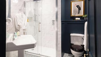 A modern bathroom with a glass-enclosed shower, a white sink, and a toilet.