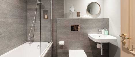 A modern bathroom with a glass-enclosed shower, a white toilet, and a sink with a mirror above.
