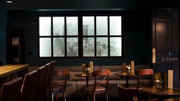 A cozy seating area with a large window overlooking a cityscape, wooden furniture, and a menu board on the wall.