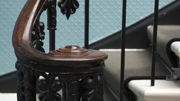 Una escalera de madera con barandales negros ornamentados y peldaños blancos.
