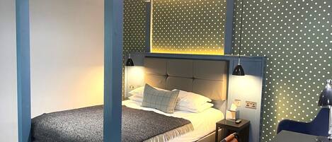 A modern bedroom with a bed, bedside tables, and a desk.