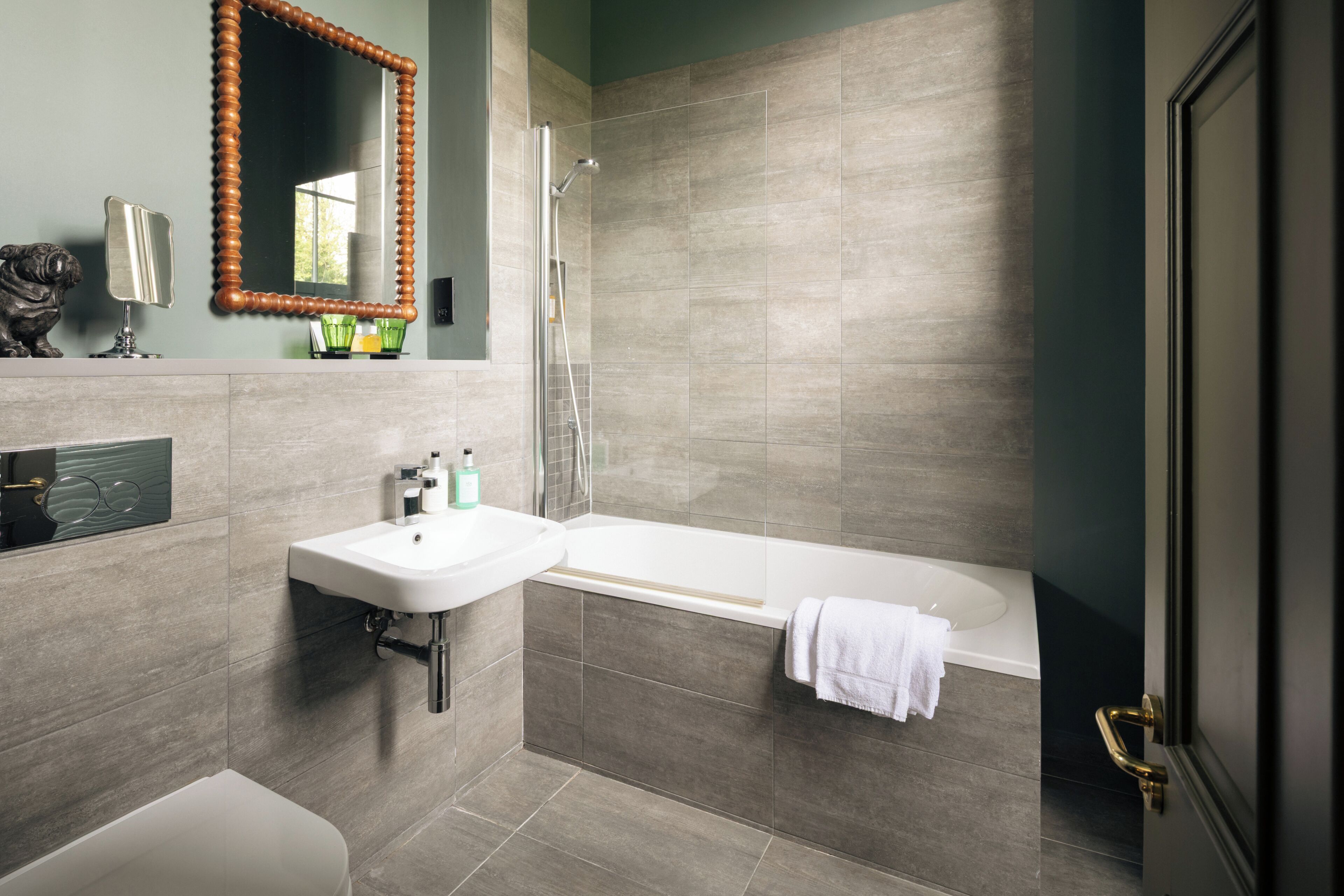 A modern bathroom with a sink, mirror, and bathtub.