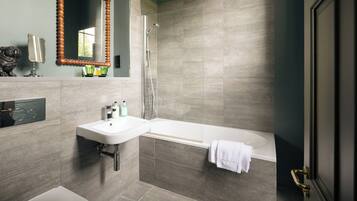 A modern bathroom with a sink, mirror, and bathtub.