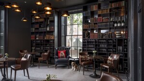 A library with leather chairs, bookshelves, and a dog. - The Churchill Hotel (York)