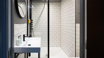 Un baño moderno con lavamanos, espejo y ducha blancos.
