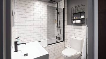 A modern bathroom with white subway tiles, a glass-enclosed shower, a white sink, and a toilet.