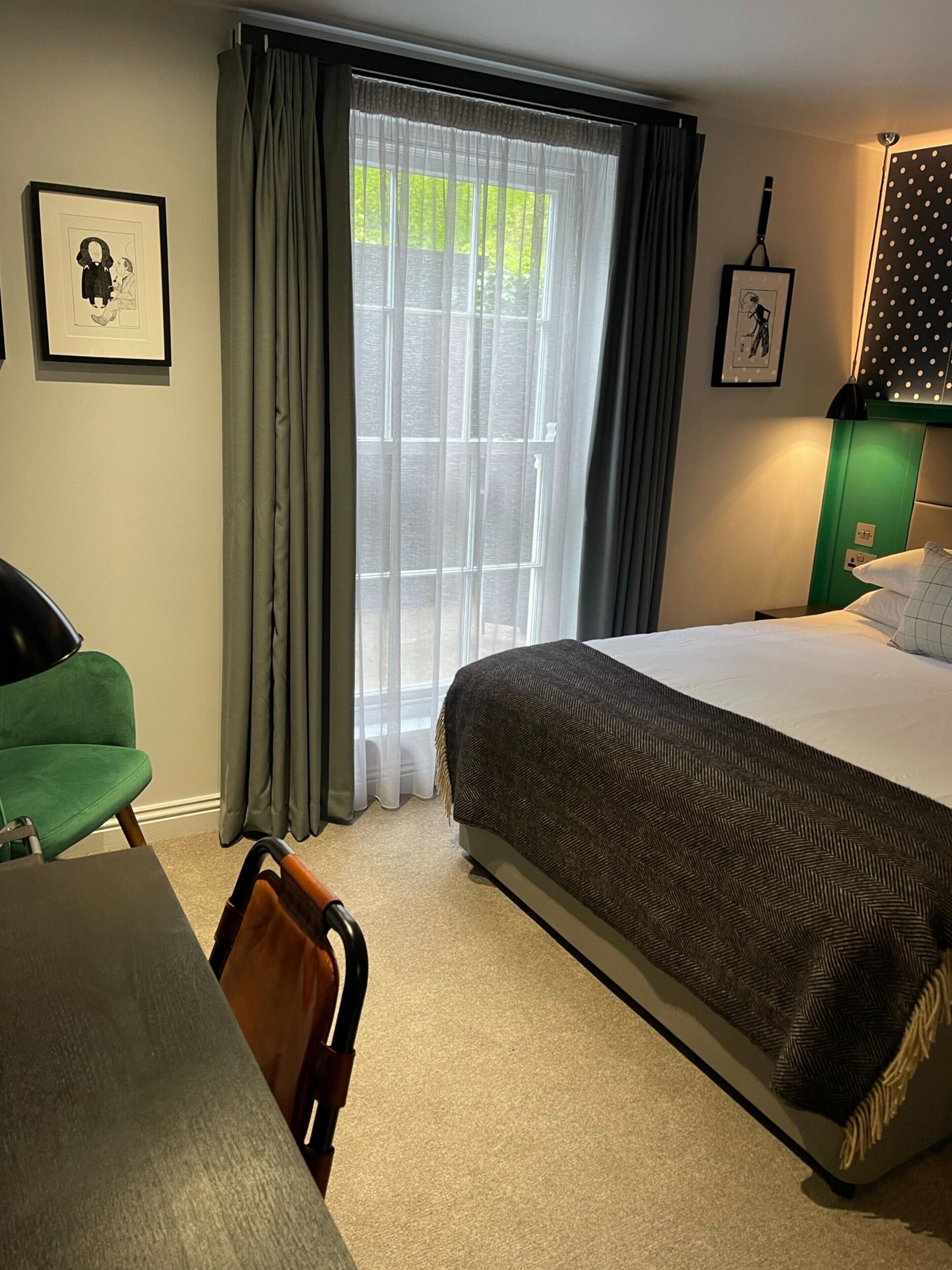 A hotel room with a large bed, a desk, a chair, and a window with curtains.