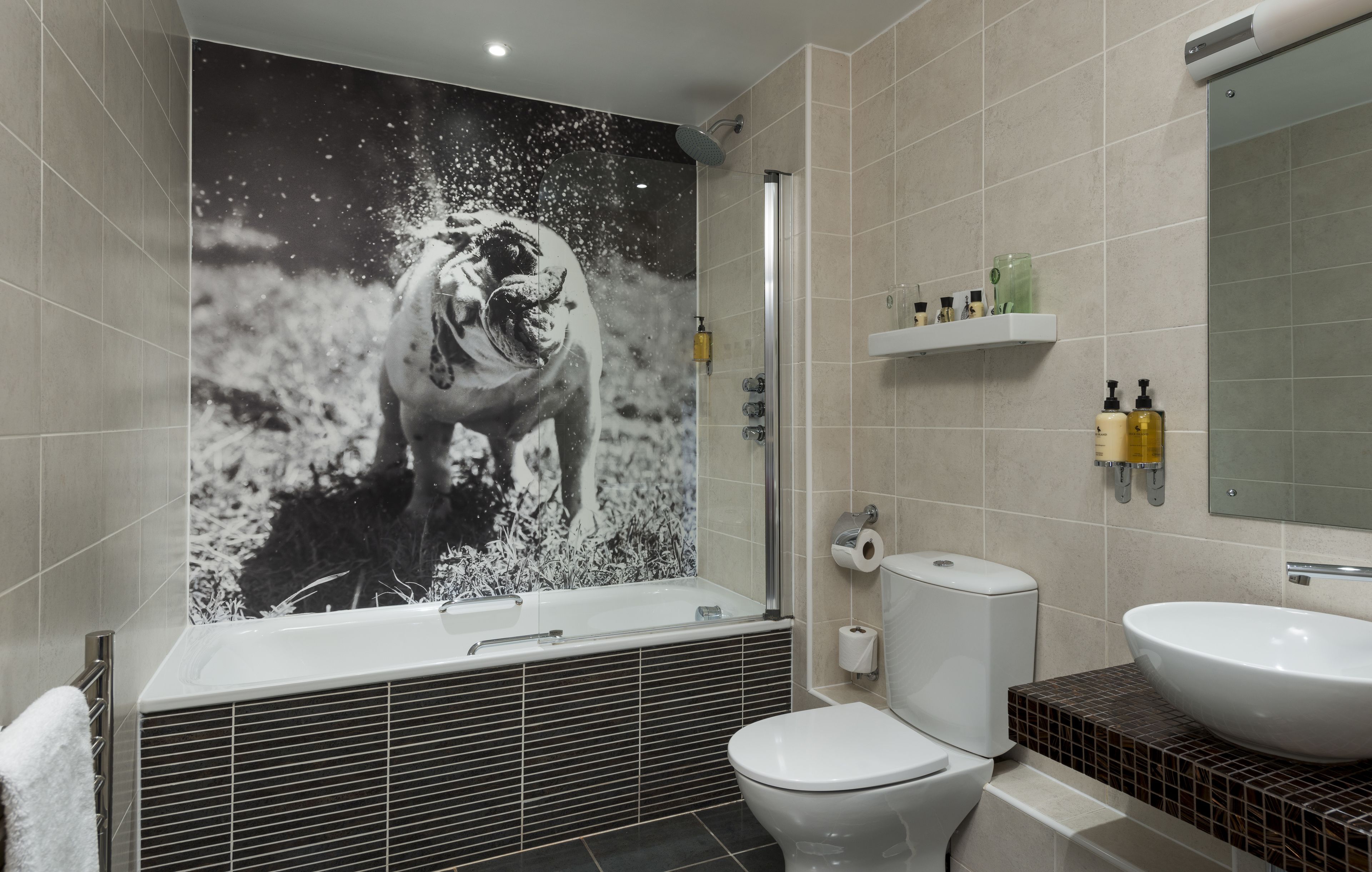 Une salle de bain moderne avec un grand miroir fixé au mur, une baignoire, des toilettes et un lavabo.