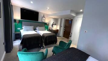 Una habitación de hotel con dos camas, un escritorio, una silla y un televisor.