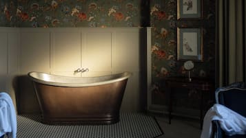 A bathroom with a freestanding bathtub, a patterned floor, and a wall with framed artwork.