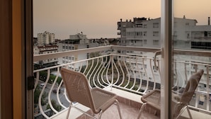 A balcony with wicker chairs and a view of a cityscape during sunset. - Dinc Hotel (Antalya)