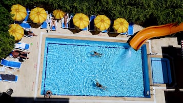 Piscina com escorregador, espreguiçadeiras e guarda-sóis.