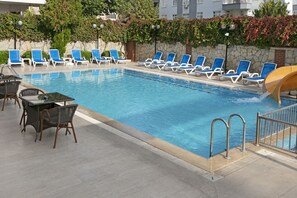 A swimming pool with blue lounge chairs and wicker tables. - Dinc Hotel (Antalya)
