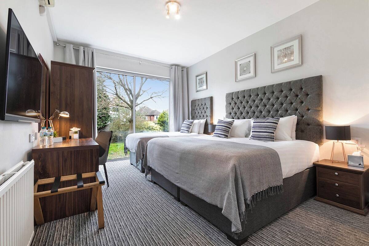 A modern bedroom with a large bed, a desk, and a TV.