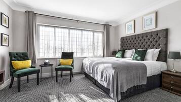 A hotel room with a large bed, two chairs, a small table, and a nightstand.