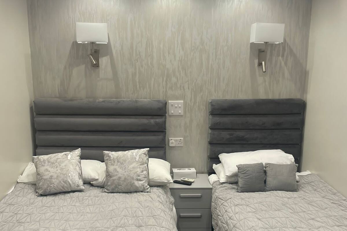 Een slaapkamer met twee bedden, elk met hoofdbord, nachtkastjes en lampen.