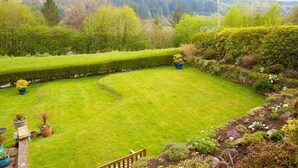Un jardin bien entretenu, avec une pelouse soigneusement taillée, une variété de plantes à fleurs et une clôture en bois.