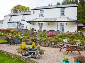 A two-story white building with a stone staircase leading to a covered patio area. - Llwyn Onn Guest House (Merthyr Tydfil)
