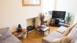 Un salon avec un canapé, une table basse et un téléviseur.