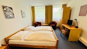 A hotel room with a double bed, two chairs, a desk with a laptop, and a large window with curtains. - City Apartment Hotel Hamburg (Hamburg)