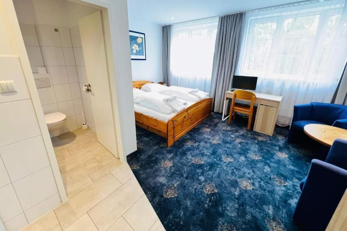Una habitación de hotel con cama, escritorio, silla, televisor y baño.