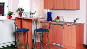 A compact kitchen with two bar stools, a coffee maker, and a sink. - City Apartment Hotel Hamburg (Hamburg)