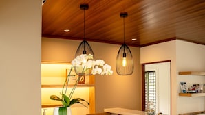 A reception area with a wooden reception desk, a vase with white flowers, and pendant lighting. - Hotel Villa Los Candiles (Santa Ana)