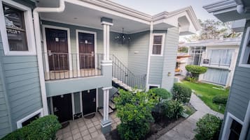 A two-story house with a covered front porch, a staircase, and a small garden area.