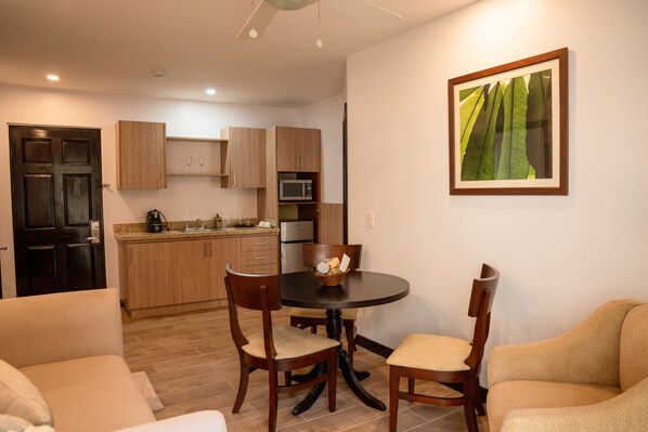A modern kitchen with wooden cabinets, a microwave, and a dining area with a round table and chairs. - Hotel Villa Los Candiles (Santa Ana)