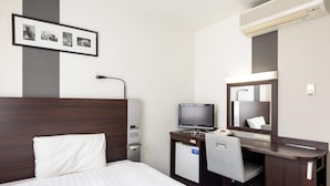 A hotel room with a bed, a desk with a computer, a chair, a desk lamp, a mirror, and a framed photo on the wall. - Comfort Hotel Shin Yamaguchi (Yamaguchi)
