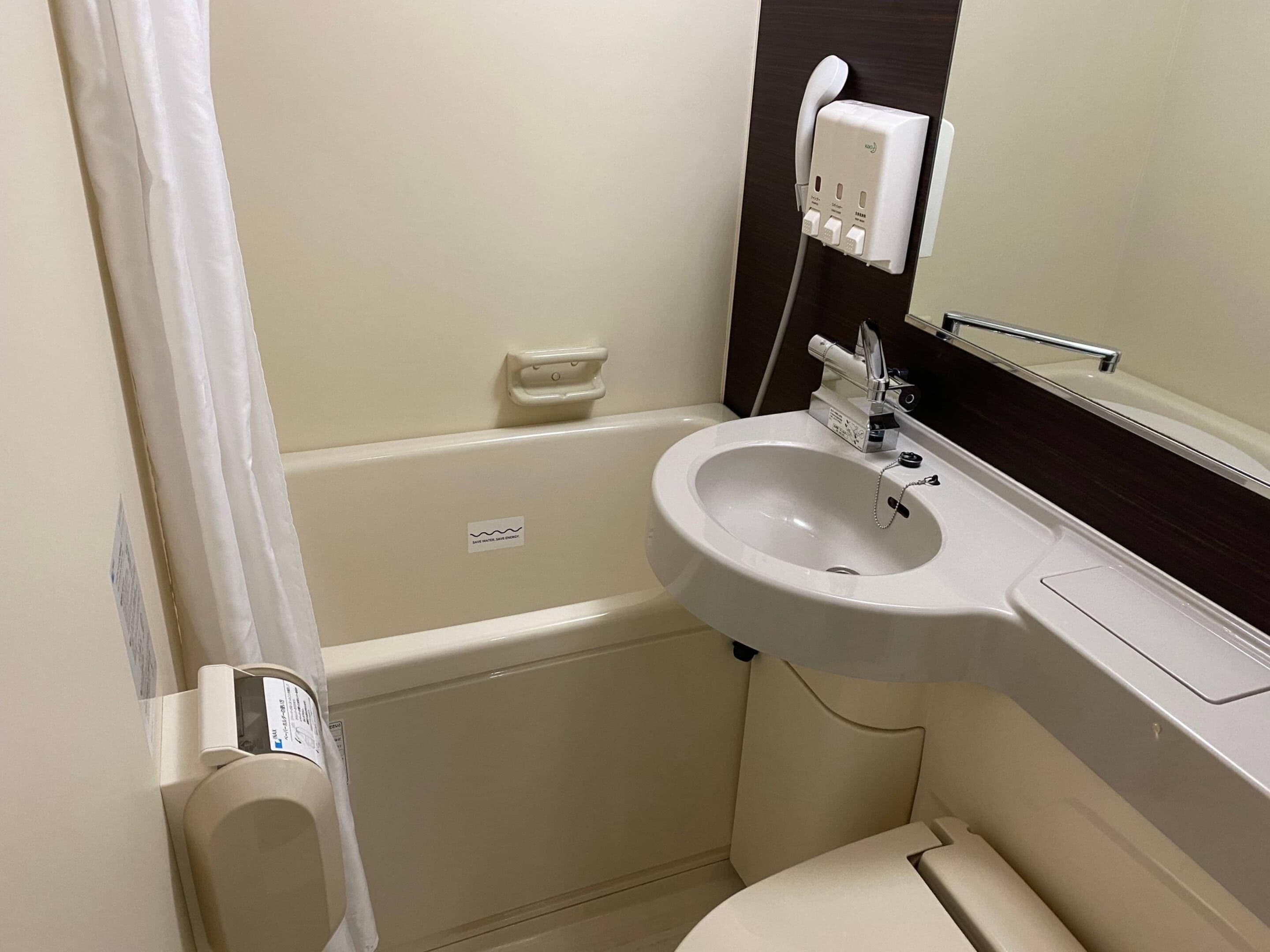 Un bagno con lavandino bianco, uno specchio, un portascopevoli e un water.