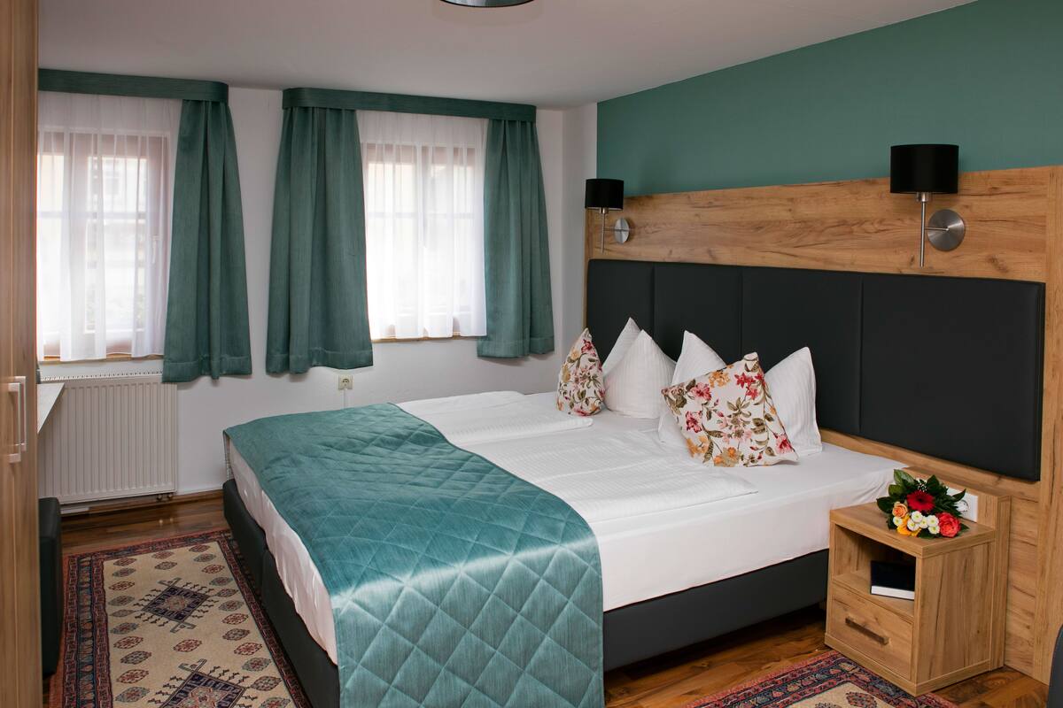 Ein ordentlich eingerichtetes Schlafzimmer mit einem Bett, Nachttischen und einem Nachtschränkchen.