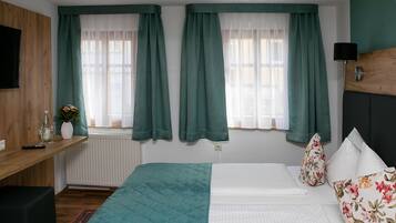 Ein Schlafzimmer mit einem Bett, einem Nachttisch, einem Schreibtisch und einem Fenster mit Vorhängen.
