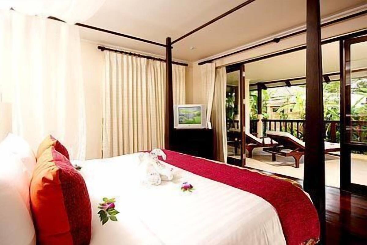 Ein Hotelzimmer mit einem großen Bett, einem Fernseher und einem Balkon mit Sitzmöbeln.