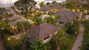 A resort with thatched-roof huts, lush greenery, and a view of the sea. - Chandara Resort & Spa Phuket (Pa Klok)