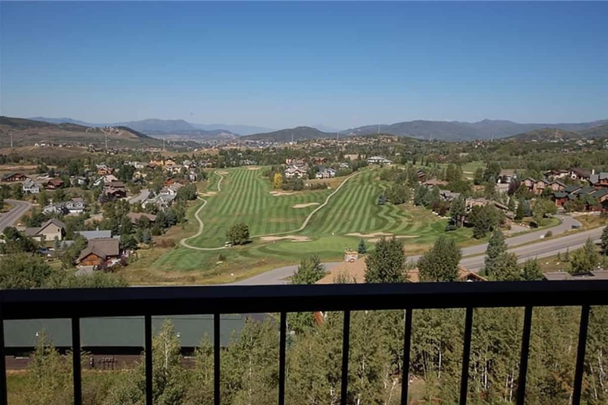 A golf course with a clear view of the surrounding residential area and distant mountains.