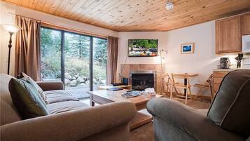 Una sala de estar acogedora con chimenea, televisor y comedor con muebles de madera.