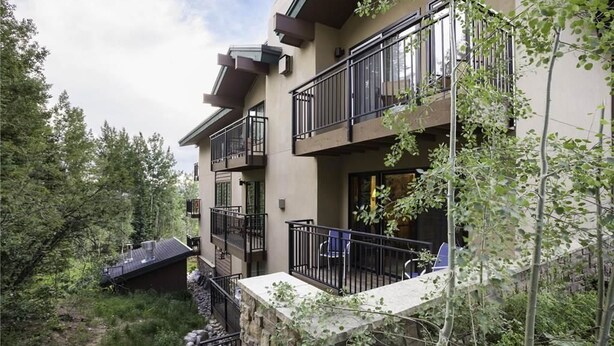 Un immeuble à plusieurs étages doté de balcons, entouré d’arbres et de verdure.