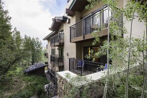 A multi-story building with balconies, surrounded by trees and greenery.