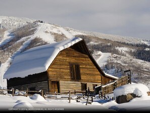 A wooden cabin with a sloped roof, surrounded by snow-covered terrain and mountains. - Scandinavian Lodge And Condominiums by Pioneer Ridge Mgmt (Steamboat Springs)