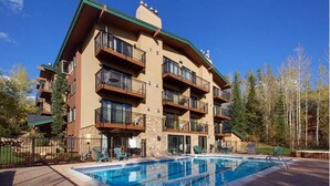 Un hôtel à plusieurs étages doté de balcons, d’une piscine et d’une terrasse en bois.