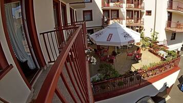 Un hotel de varios pisos con balcones, mobiliario exterior y un patio cubierto.