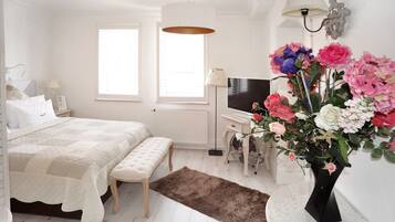 A bedroom with a bed, bedside table, TV, and a large floral arrangement.