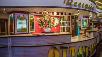 A hotel reception area with a large sign reading "Recepcia" and a floral arrangement on the counter.